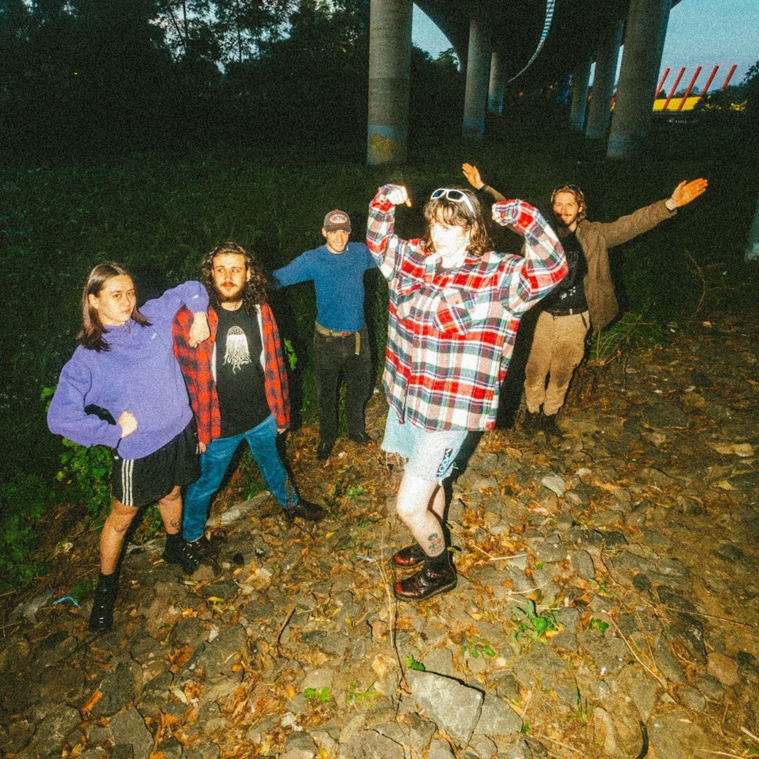 A colourful group of people standing under a freeway